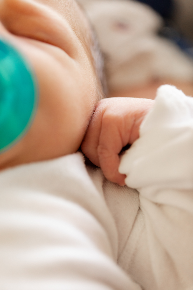 newborn with a hospital pacifier, highlighting his relaxed hand resting near his cheek