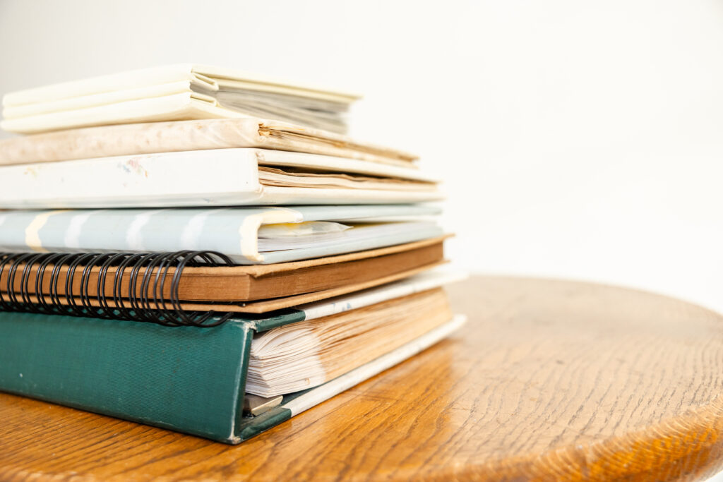 Stack of six printed photo albums, showing different styles, textures, and sizes.