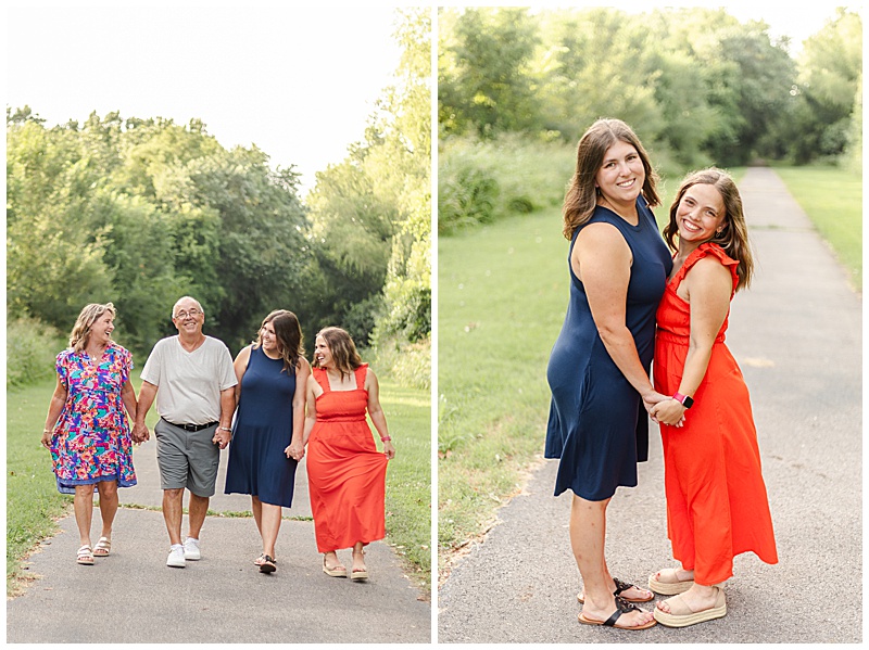 Mother, father, and two adult daughters holding hands and laughing while walking down a wooded trail; daughters share a playful moment, leaning toward each other and smiling at the camera during an outdoor family session.