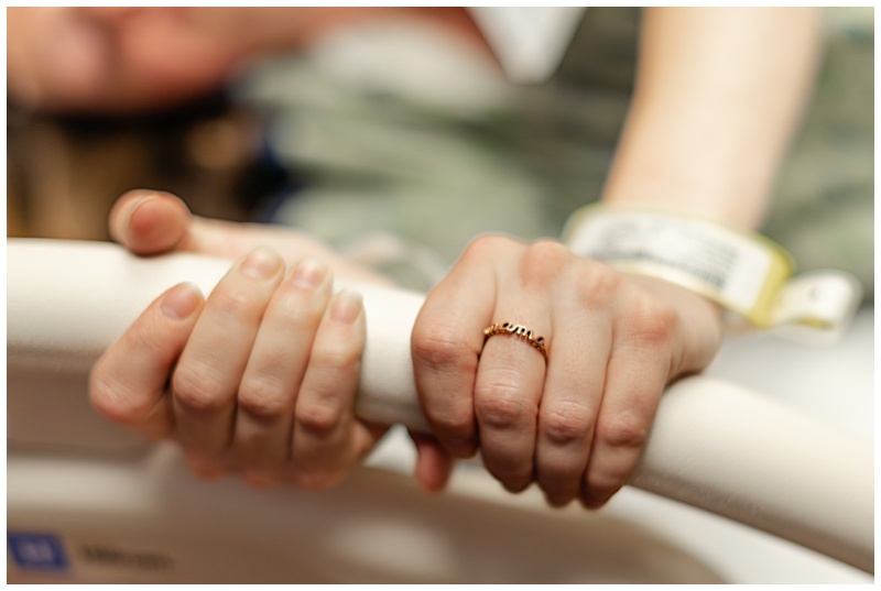 Detail photograph of a laboring mother's hands with a "Mama" ring during birth